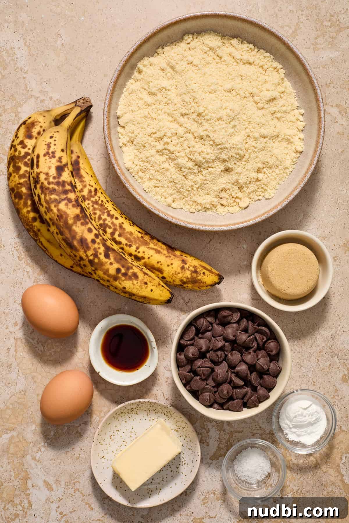 Almond Flour Banana Muffins Recipe — Moist Gluten-Free Muffins 3 Butter, baking powder, bananas, brown sugar and other ingredients arranged on counter.