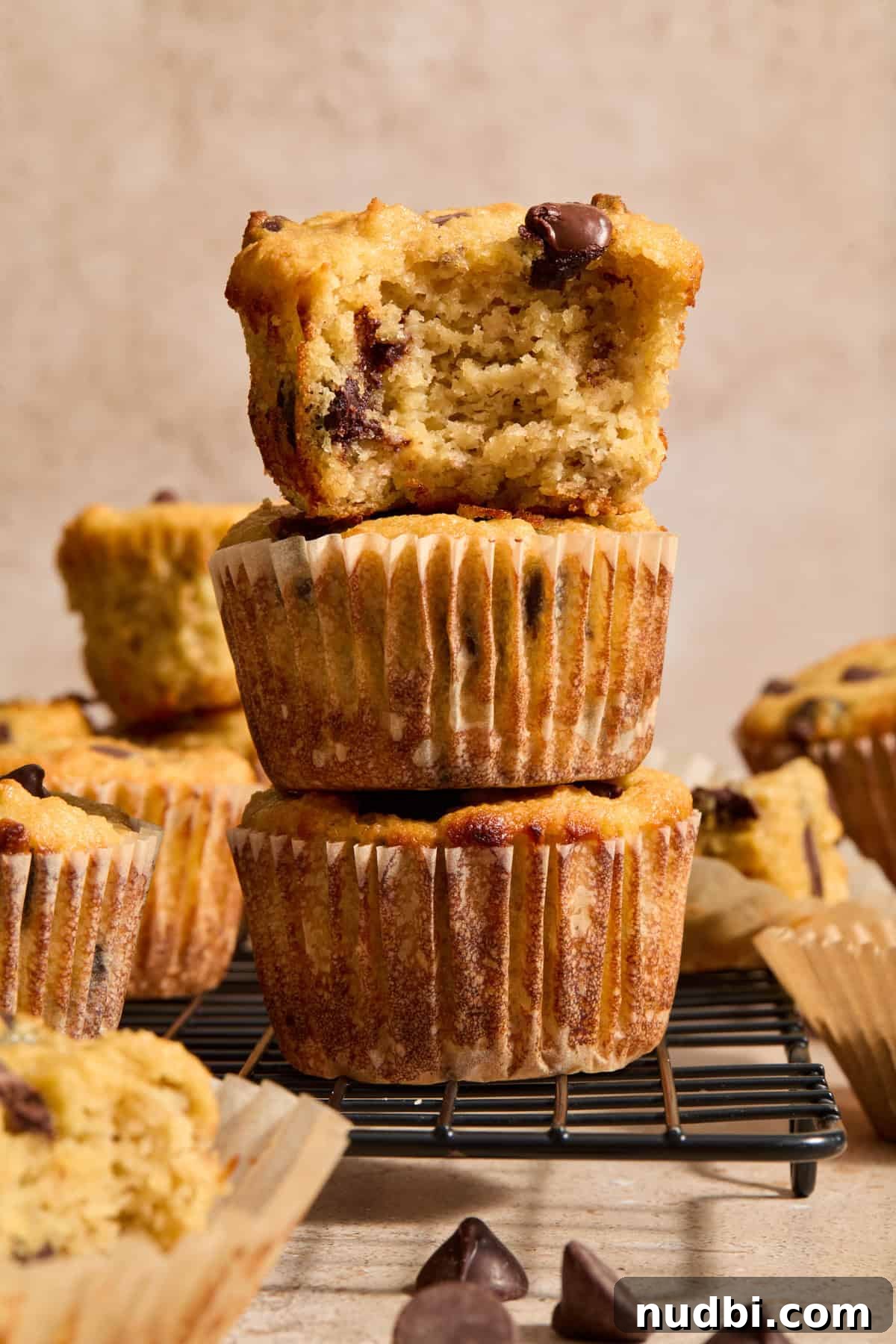 Almond Flour Banana Muffins Recipe — Moist Gluten-Free Muffins 5 Stack of almond flour banana bread muffins with chocolate chips with bite taken out of top muffin.