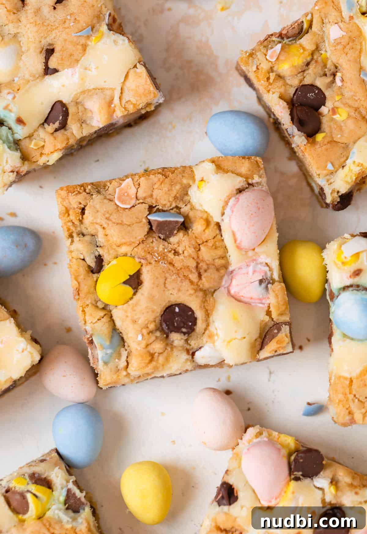 Mini Egg Cheesecake Cookie Bars Recipe for Spring Desserts 2 Mini egg bars with chocolate chips and cheesecake swirl cut with mini eggs surrounding.