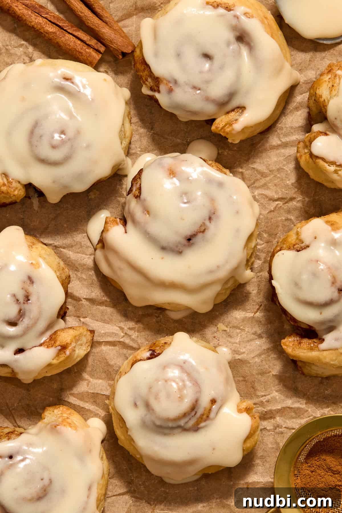 Quick Puff Pastry Cinnamon Rolls with Sticky Cinnamon Glaze 12 Iced cinnamon rolls on parchment paper.