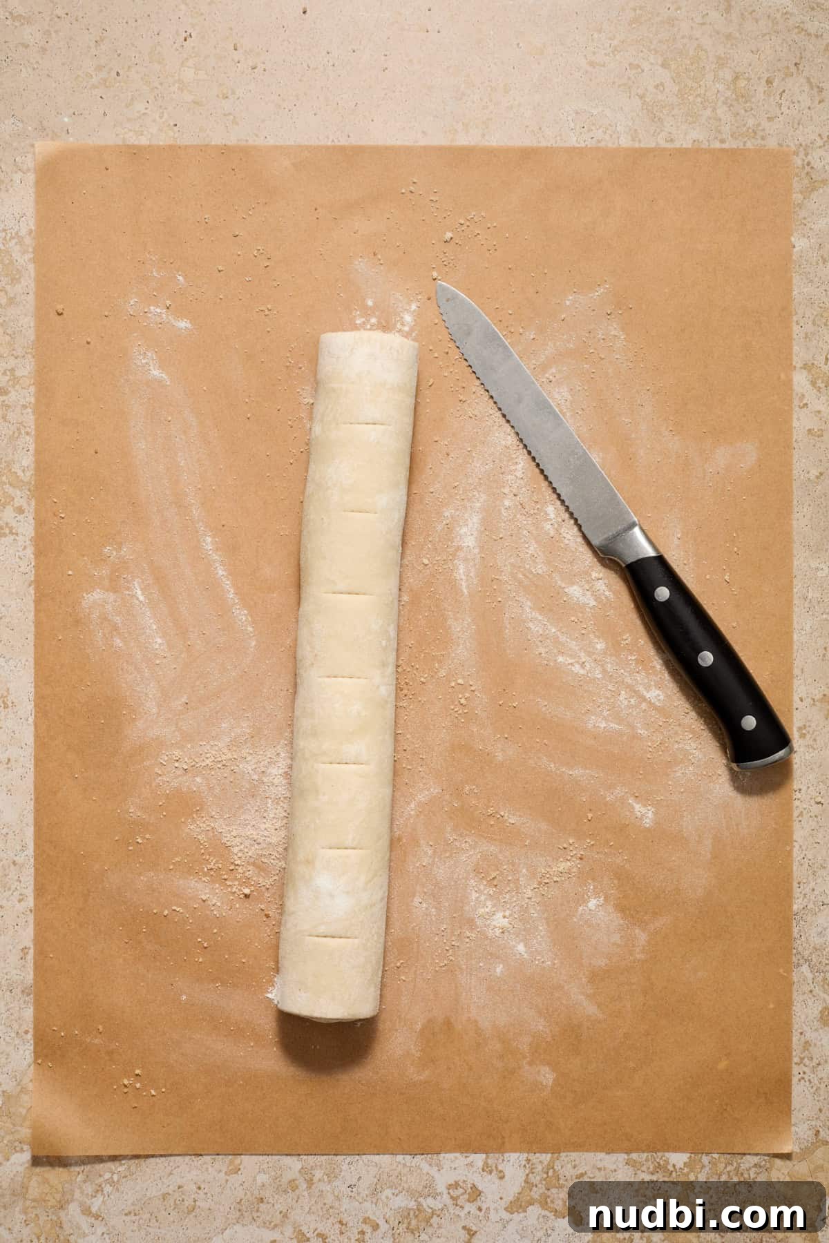 Quick Puff Pastry Cinnamon Rolls with Sticky Cinnamon Glaze 8 Lines cut on cinnamon roll log on parchment.