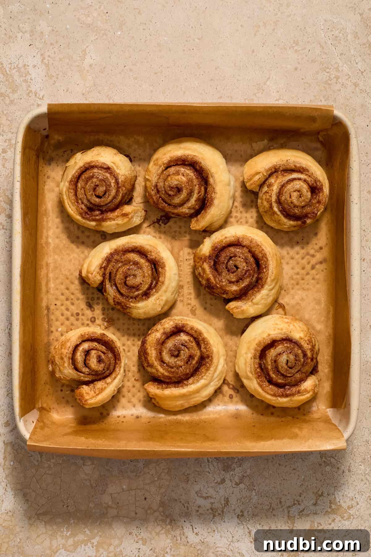 Quick Puff Pastry Cinnamon Rolls with Sticky Cinnamon Glaze 10 Baked puff pastry cinnamon rolls in pan.