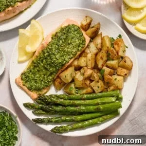 Pesto Salmon Sheet-Pan Dinner with Roasted Veggies 7 Pesto salmon dinner on white plate with potatoes, asparagus and two lemon slices.