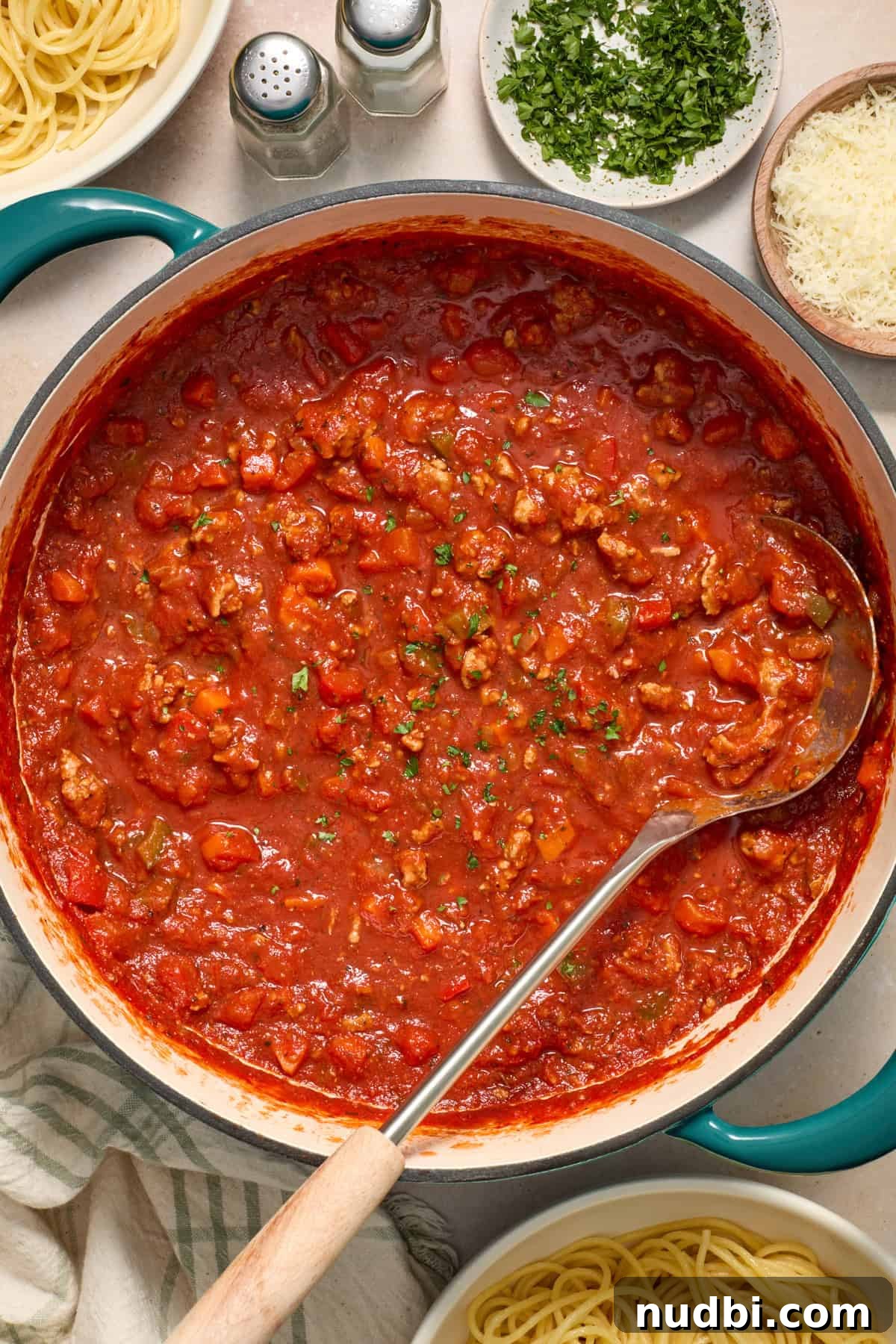 Savory Ground Turkey Spaghetti Sauce Recipe 11 Ground turkey meat sauce in pot with ladle topped with parsley.