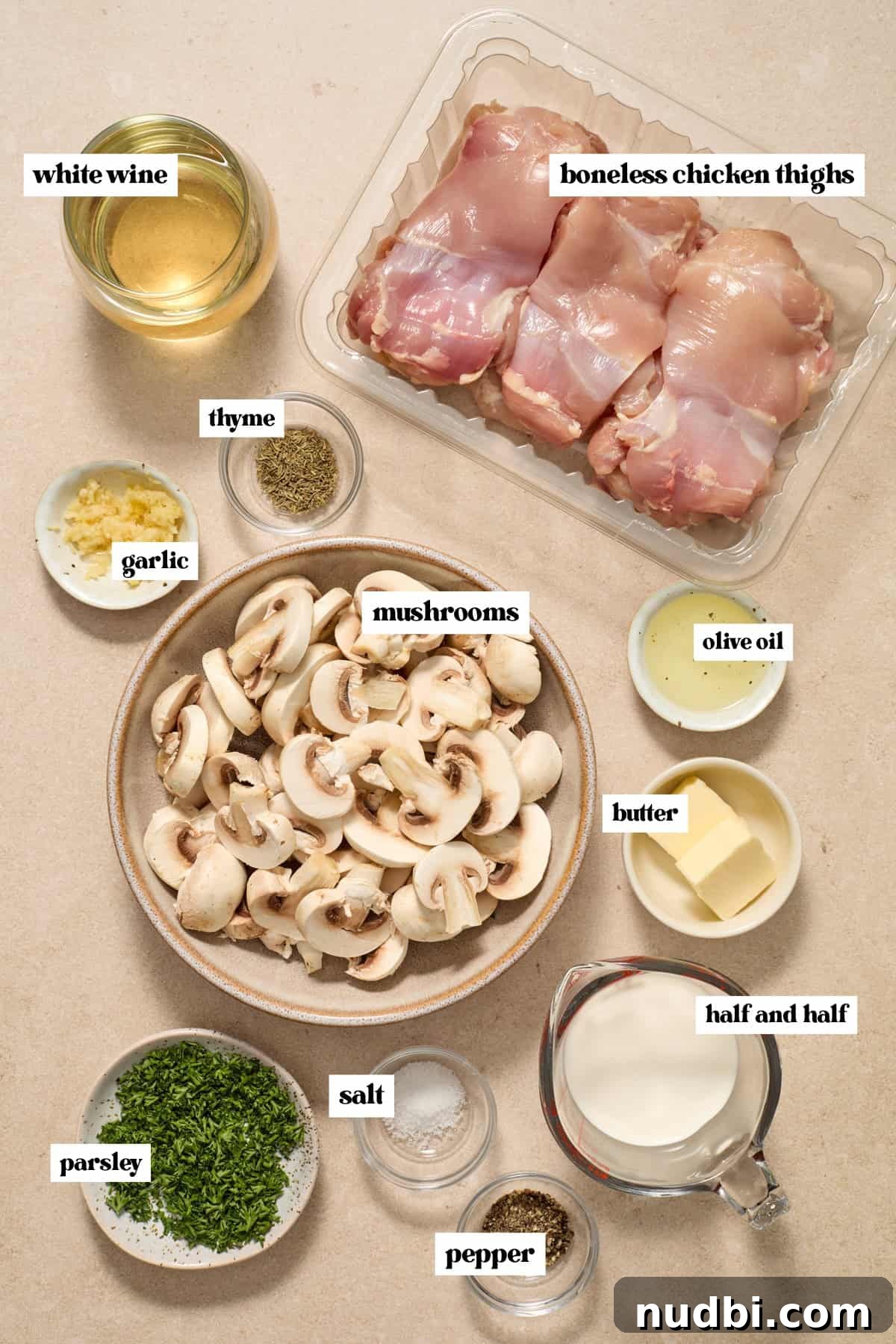 Creamy Mushroom Chicken Thighs with Garlic and Herbs 3 Chicken thighs, white wine, garlic, butter and ingredients labeled on surface.