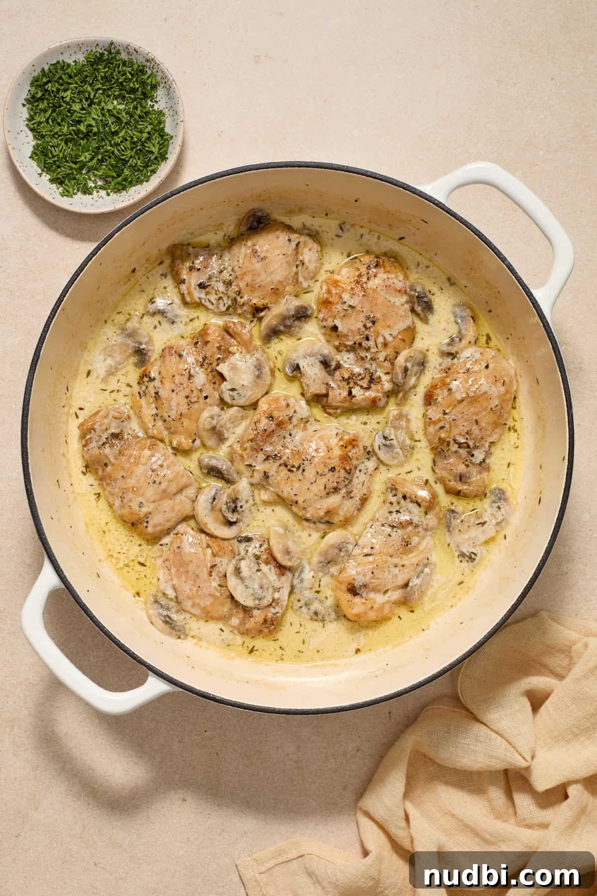 Creamy Mushroom Chicken Thighs with Garlic and Herbs 8 Cream added to chicken thighs and mushrooms in pan.