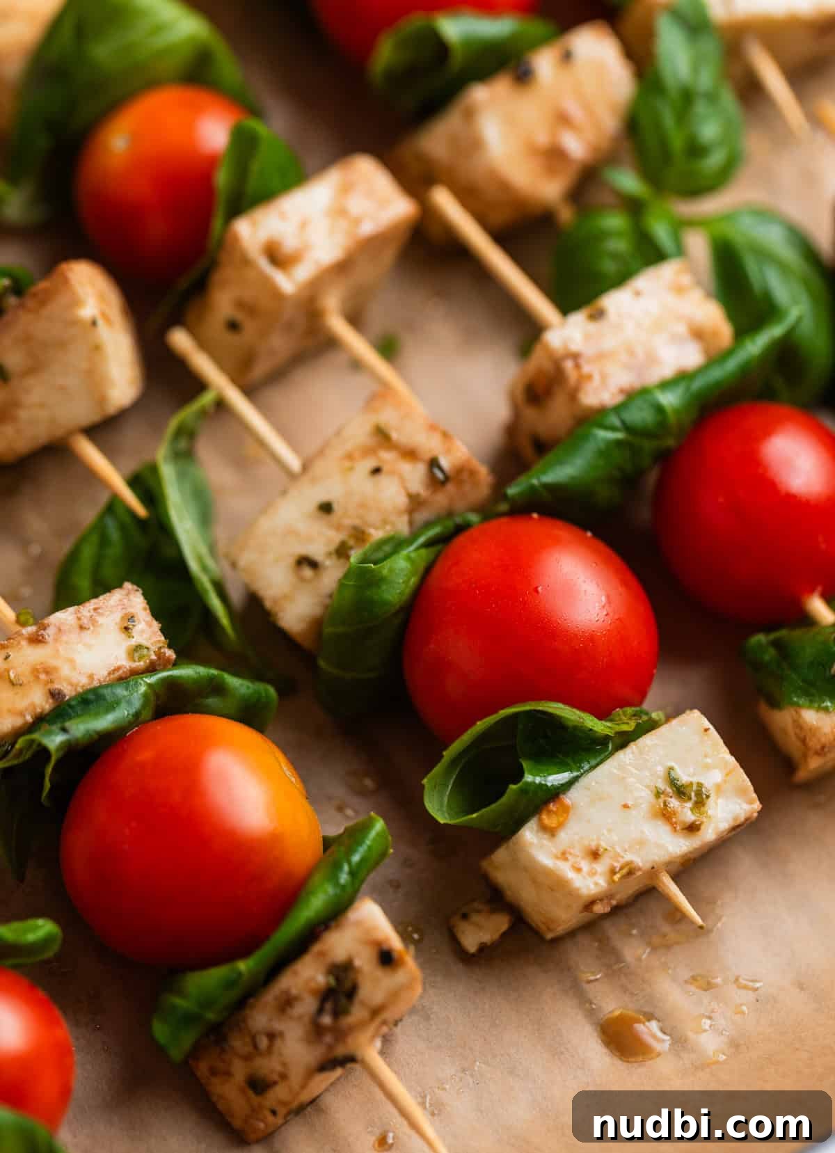 Marinated Mozzarella, Tomato & Basil Skewers for Entertaining 2 Tomato mozzarella basil skewers on parchment lined tray.
