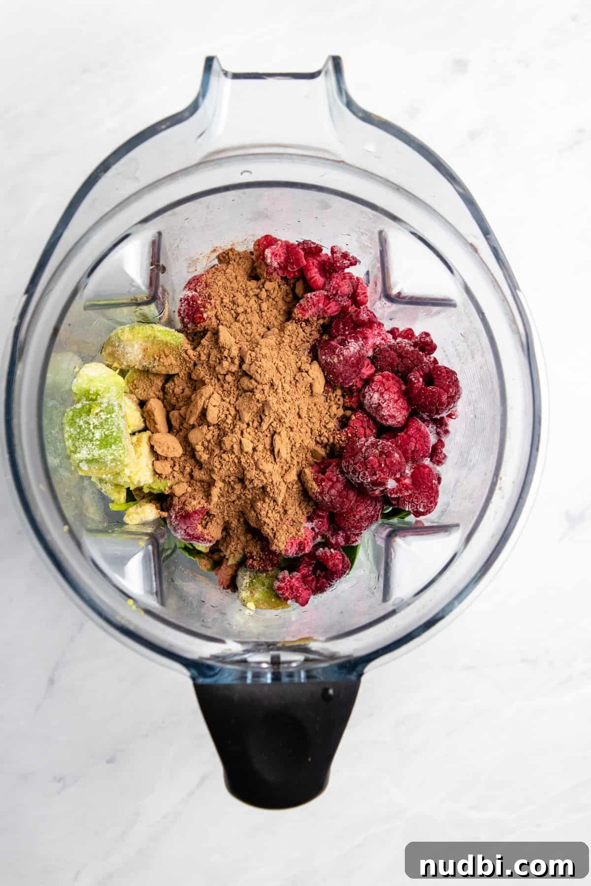 Creamy Chocolate Raspberry Smoothie with Avocado Boost 4 Overhead view of blender with avocado, raspberries, cocoa powder etc.