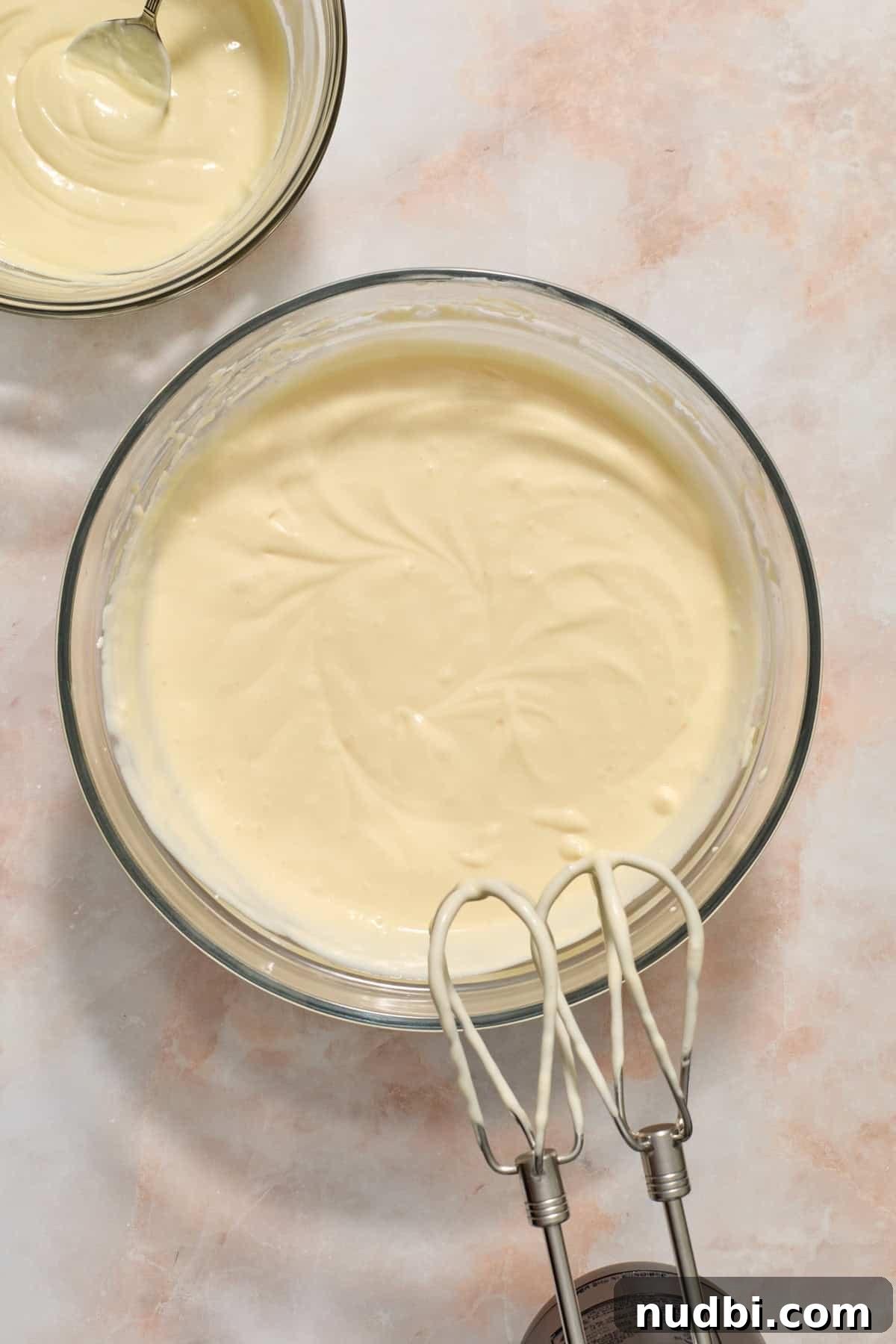 White Chocolate Raspberry Cheesecake Bars Recipe 12 Cheesecake mixture with melted white chocolate beside bowl in a smaller bowl.