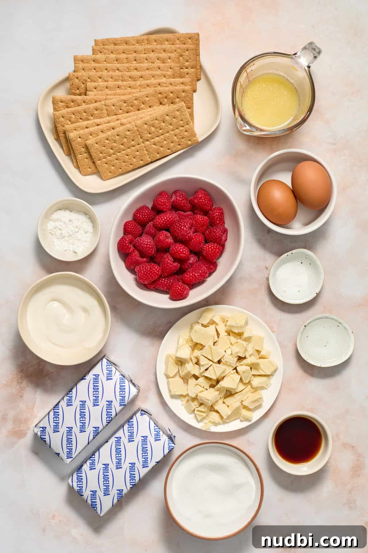 White Chocolate Raspberry Cheesecake Bars Recipe 4 Graham crackers, eggs, cream cheese, raspberries and other ingredients for recipe on a surface.