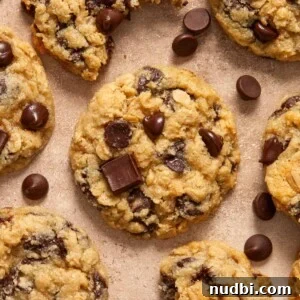 Gluten-Free Almond Flour Oatmeal Chocolate Chip Cookies 12 Oatmeal chocolate chip cookies arranged on surface with chocolate chips surrounding.