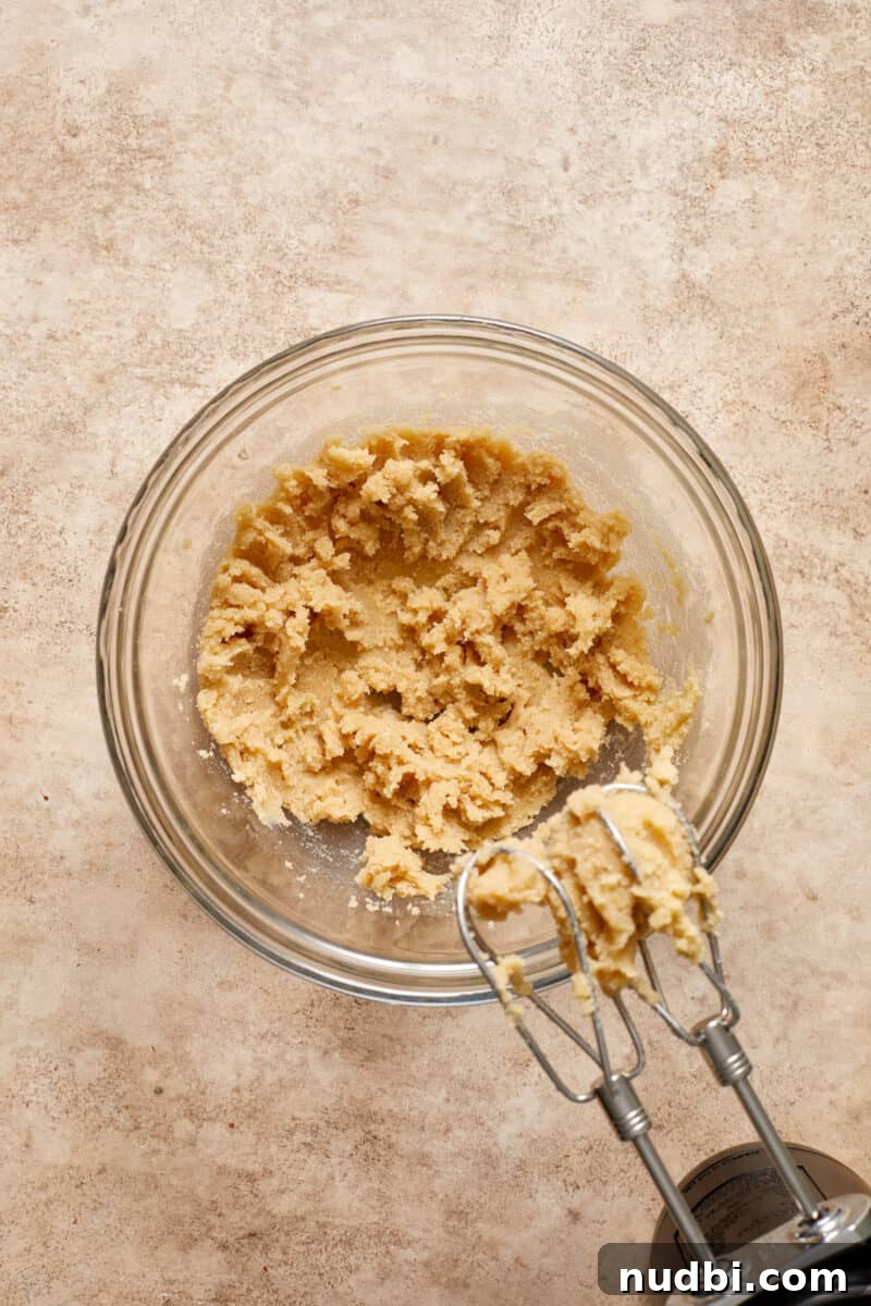 Gluten-Free Almond Flour Oatmeal Chocolate Chip Cookies 5 Creamed butter and sugar in mixing bowl with electric mixer beside bowl.
