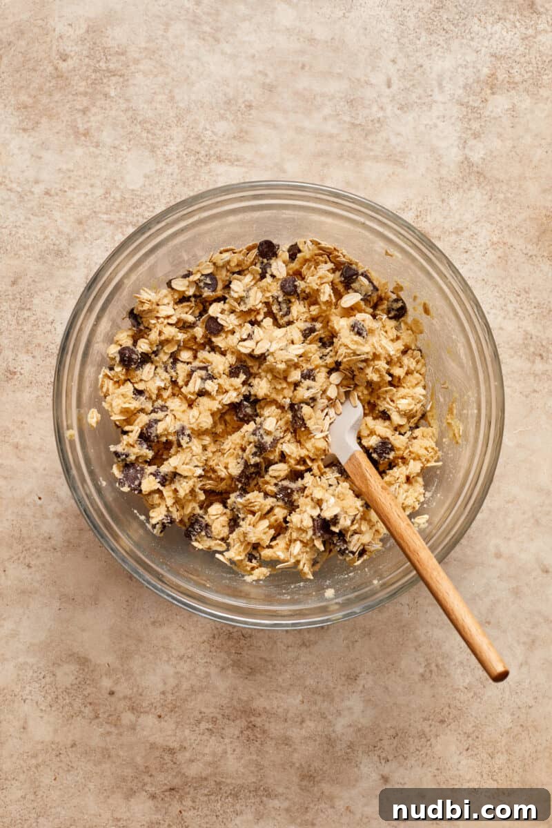 Gluten-Free Almond Flour Oatmeal Chocolate Chip Cookies 8 Almond flour oatmeal chocolate chip cookie dough in glass mixing bowl with spatula.