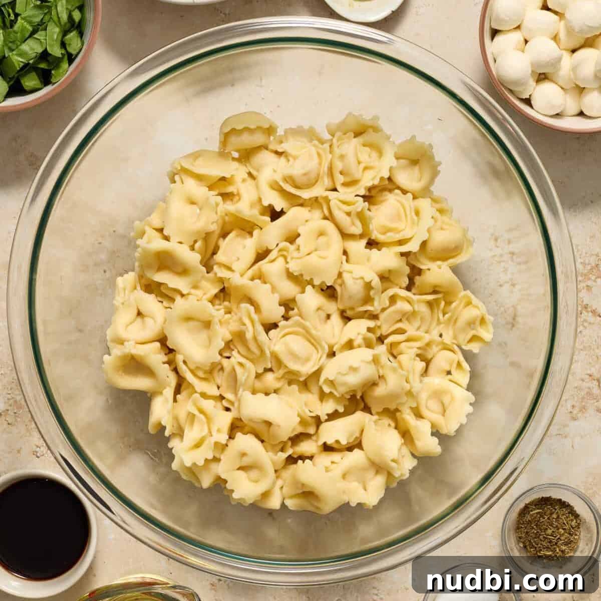 Caprese Tortellini Salad with Cherry Tomatoes and Basil 5 Cooked cheese tortellini in glass bowl.