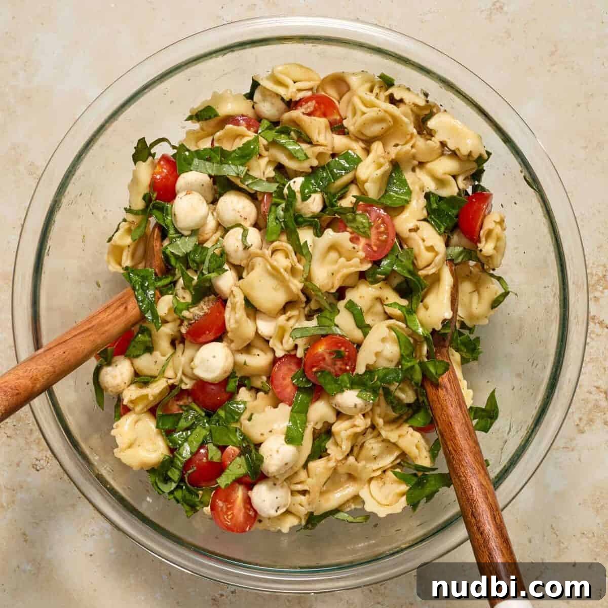 Caprese Tortellini Salad with Cherry Tomatoes and Basil 8 Tossed tortellini caprese pasta salad with salad tongs.