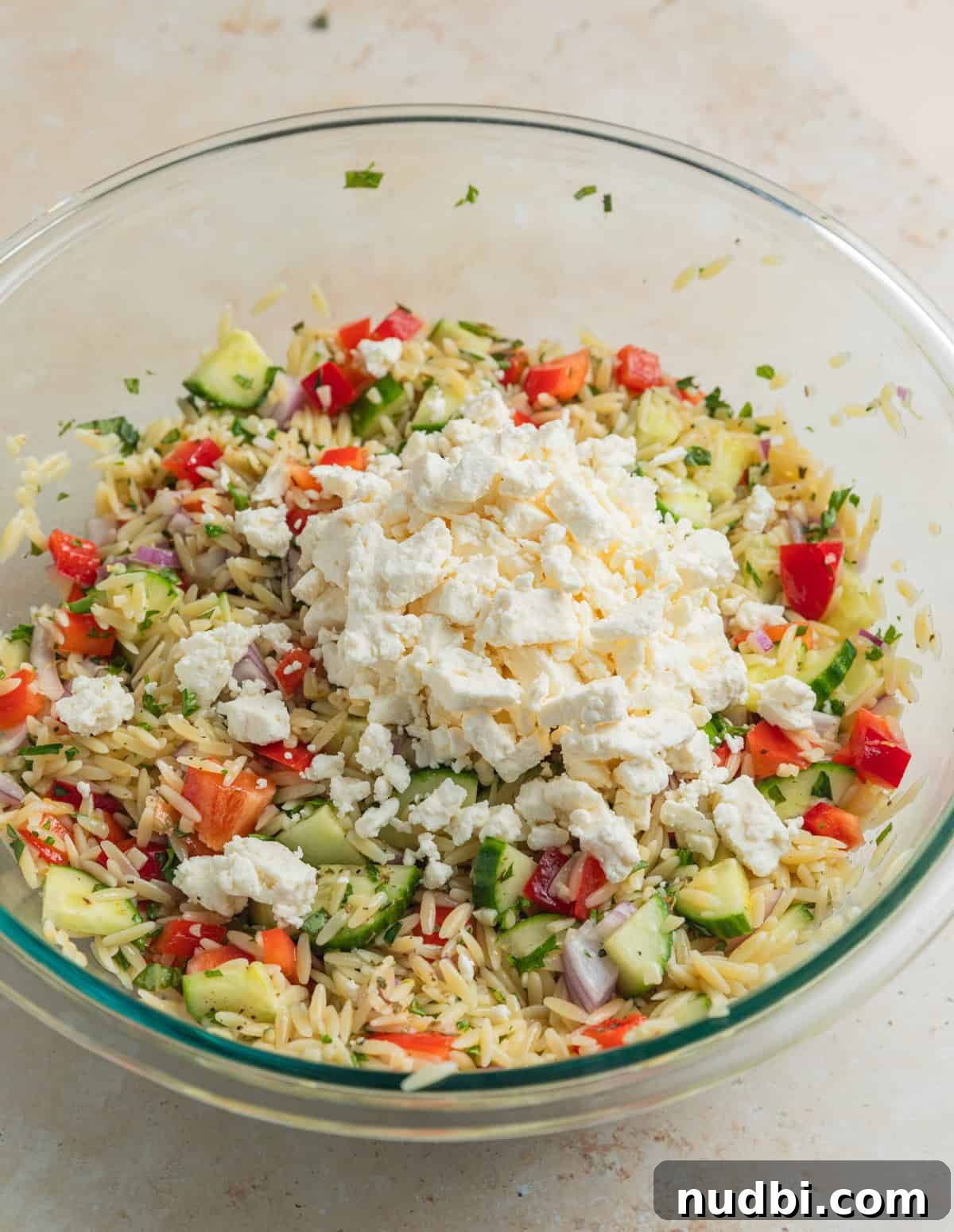 Lemon Orzo Salad with Feta, Herbs & Olive Oil Dressing 7 Feta added over top of salad mixture in bowl.