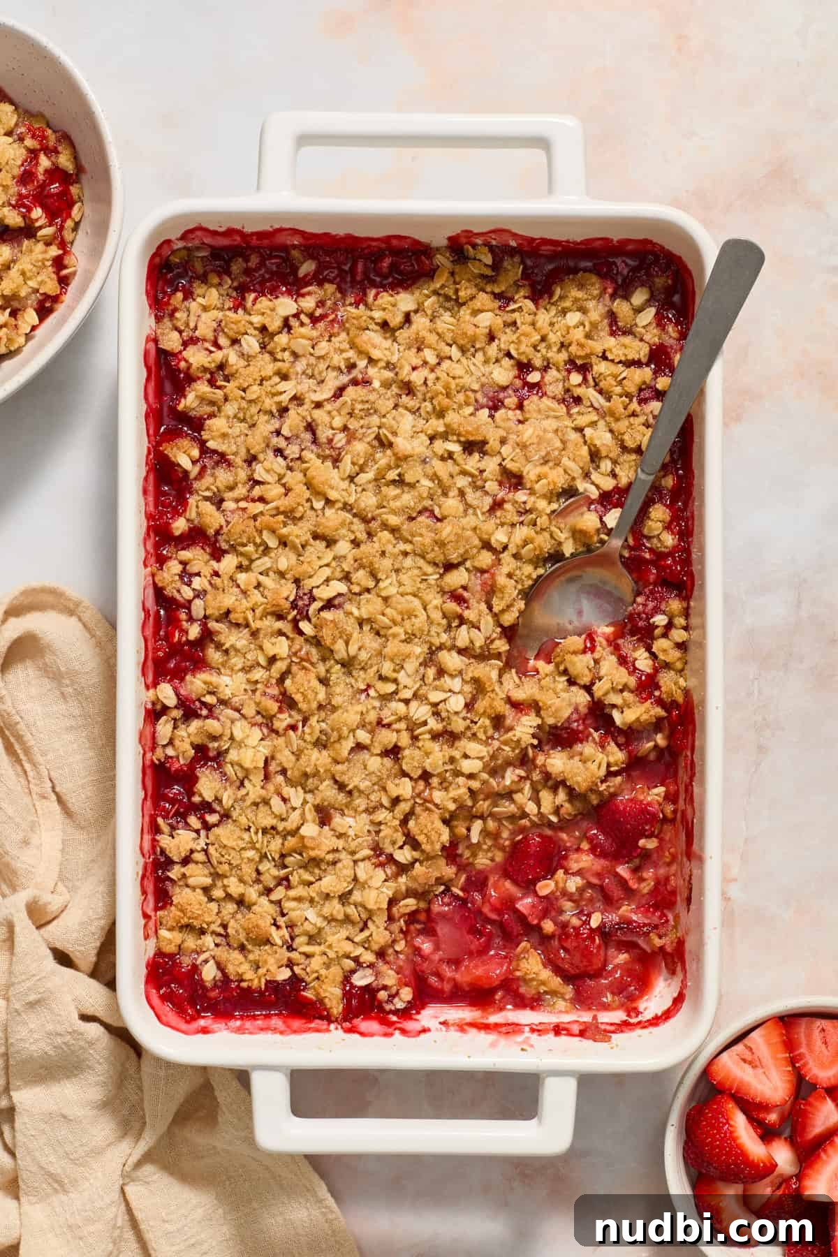 Strawberry Crumble Recipe with Buttery Oat Topping 11 Overhead view of strawberry crumble in pan with spoon inside.