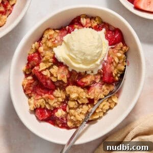 Strawberry Crumble Recipe with Buttery Oat Topping 12 Strawberry crumble served in bowl with a scoop of ice cream and spoon scooping in.
