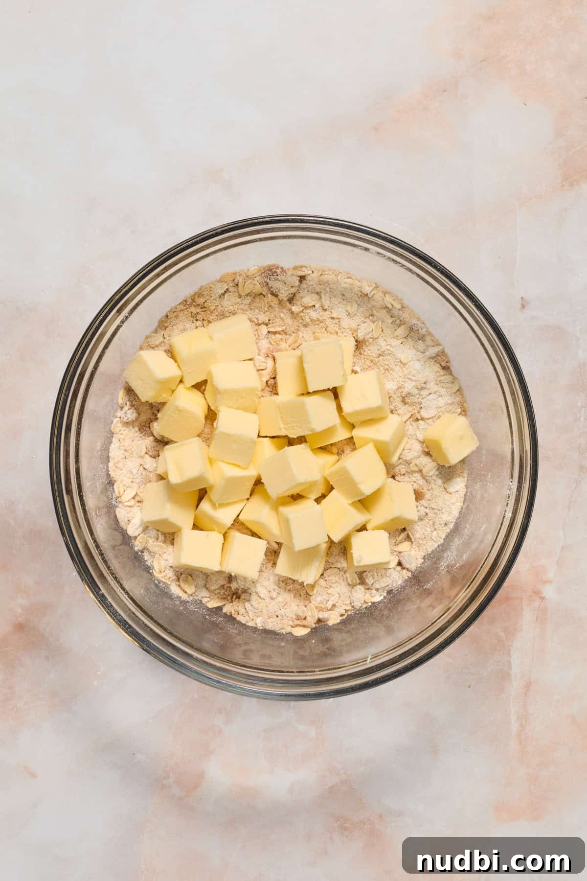 Strawberry Crumble Recipe with Buttery Oat Topping 6 Butter cubes added to bowl with crumble oat mixture.