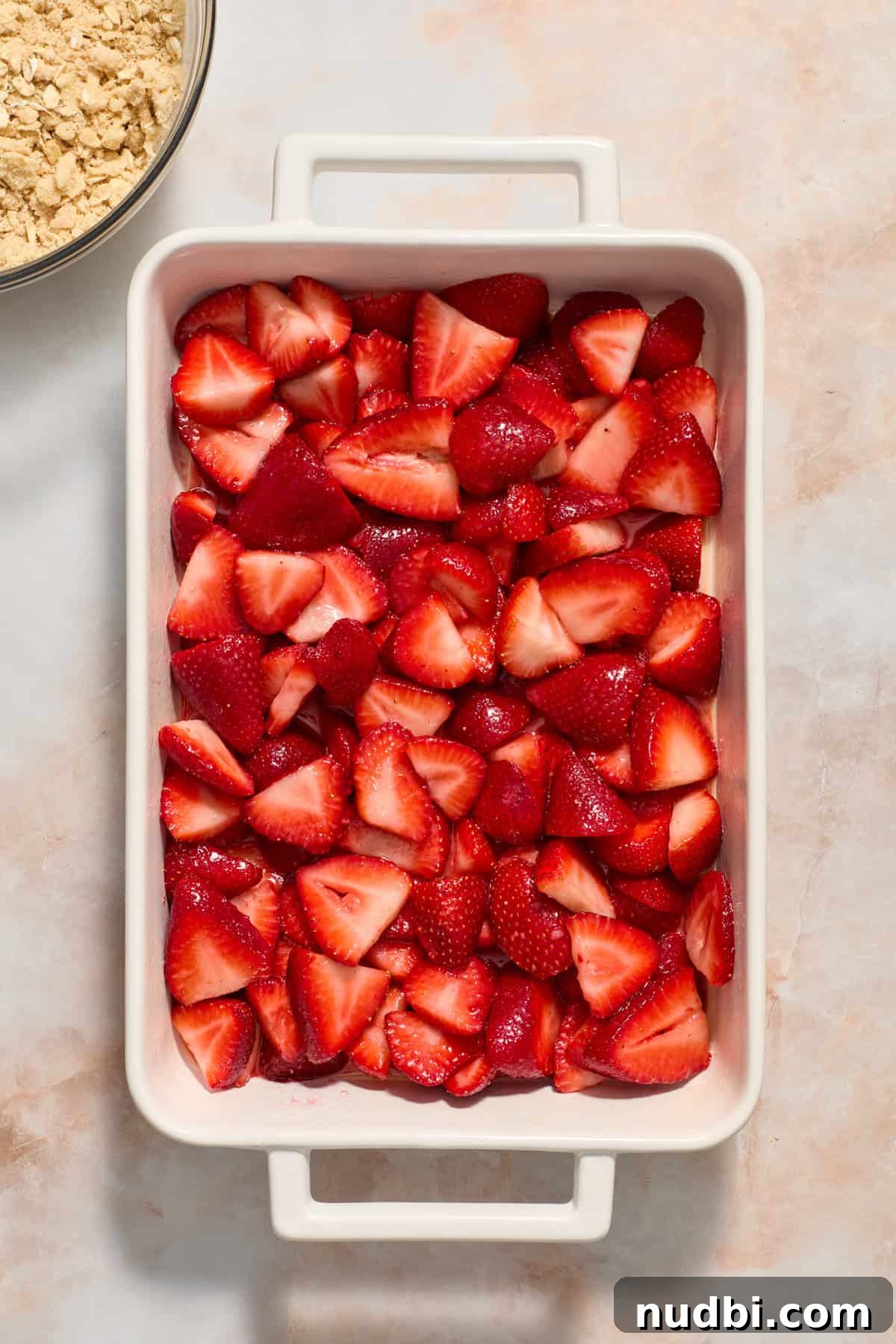 Strawberry Crumble Recipe with Buttery Oat Topping 8 Strawberries tossed in sugar and corn starch in the bottom of baking pan.