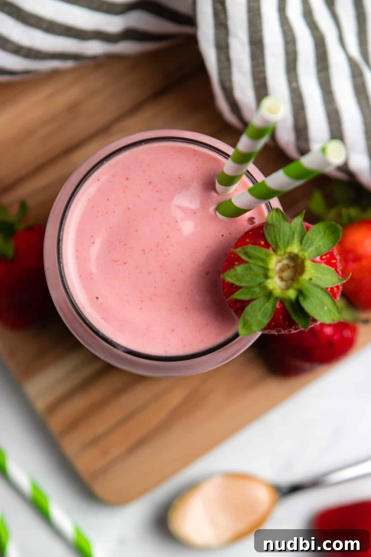 Strawberry Peanut Butter Smoothie Recipe for Creamy Protein Boost 2 Overhead view of strawberry peanut butter smoothie on wood board with straw.