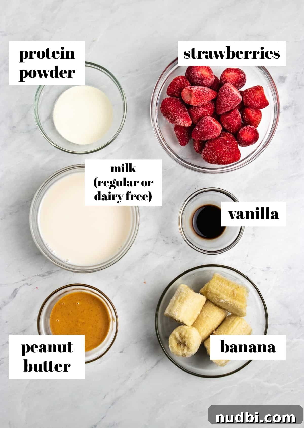 Strawberry Peanut Butter Smoothie Recipe for Creamy Protein Boost 3 Peanut butter, banana, strawberries, vanilla and ingredients labeled on counter.