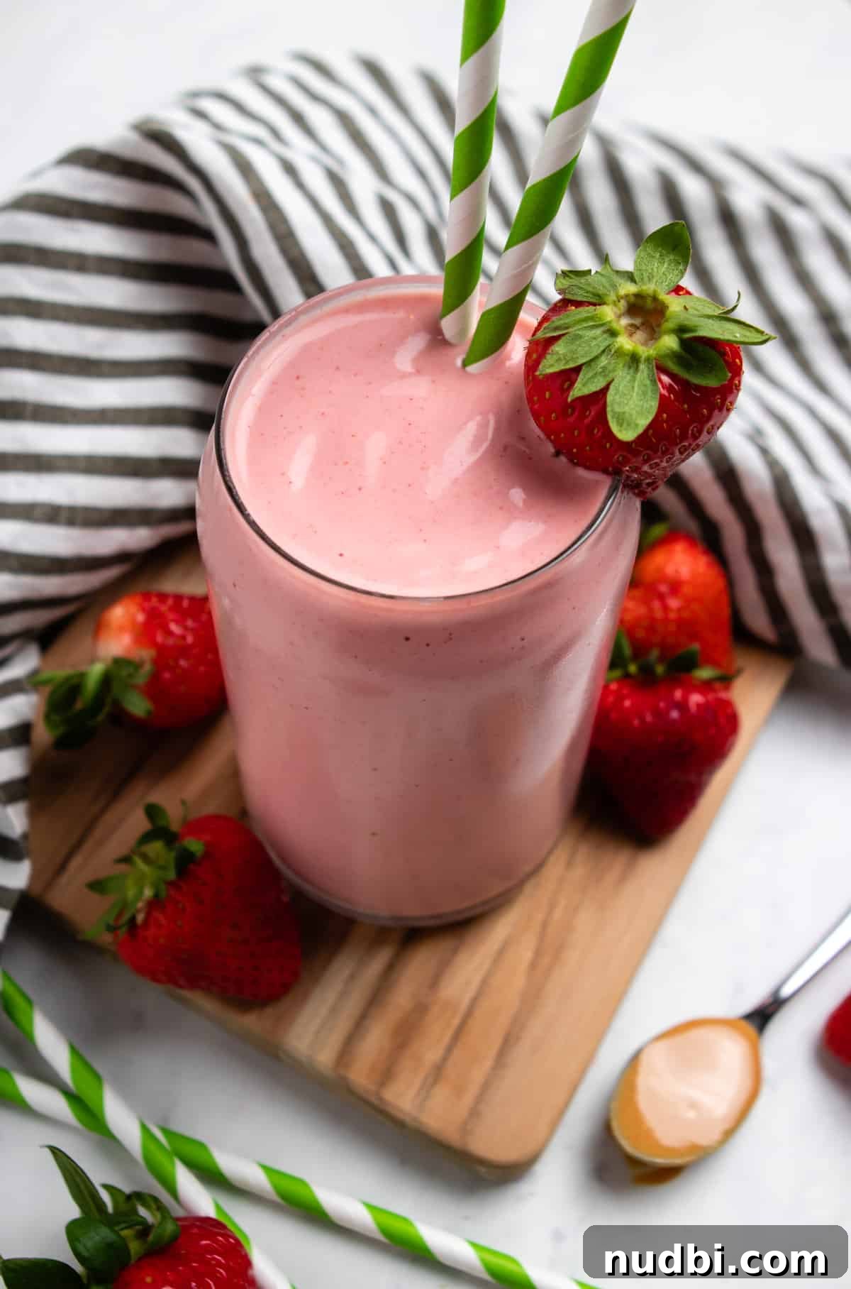 Strawberry Peanut Butter Smoothie Recipe for Creamy Protein Boost 5 Strawberry Peanut butter smoothie in glass with green straws and strawberry garnish.