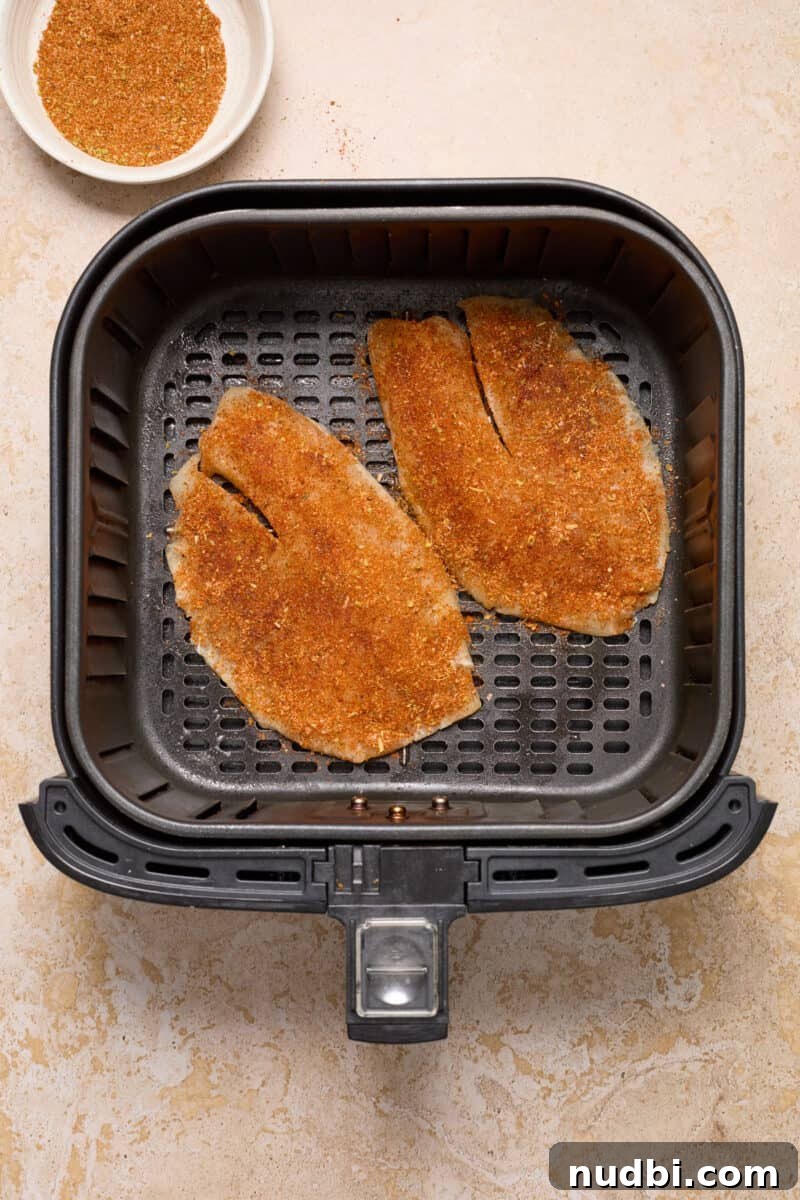 Crispy Air Fryer Fish Tacos with Cilantro-Lime Slaw 5 Fish tacos in air fryer with seasoning covering the fish.