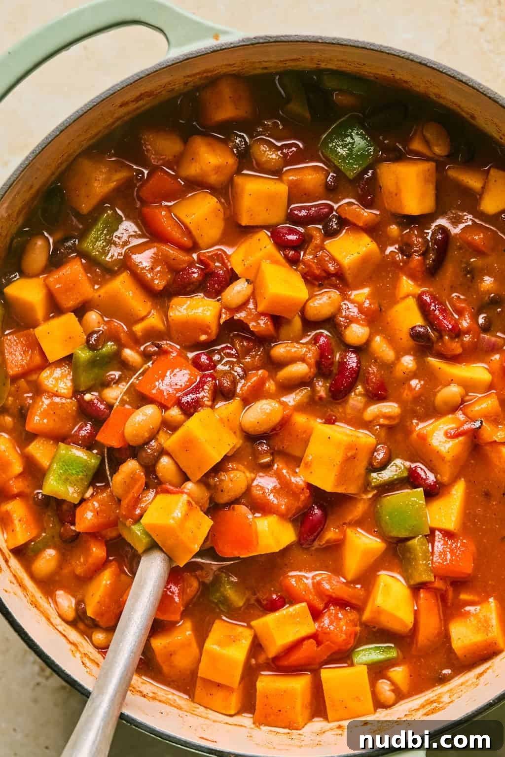 Hearty Butternut Squash Chili Recipe for Cozy Weeknights 7 Cooked butternut squash chili in pot with spoon scooping into it.
