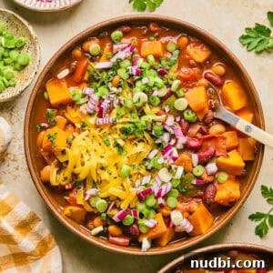 Hearty Butternut Squash Chili Recipe for Cozy Weeknights 9 Overhead view of bowl with butternut squash chili with spoon scooping into the bowl.