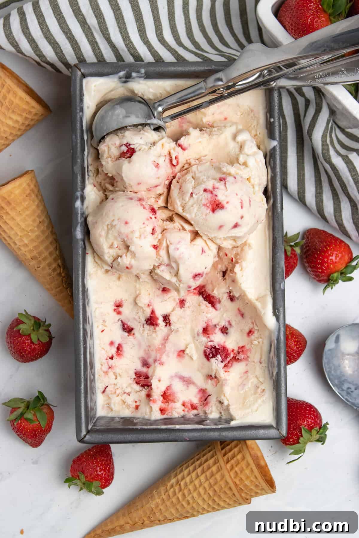 Creamy No-Churn Strawberry Ice Cream Recipe 6 Strawberry ice cream in bread pan with ice cream scoop.