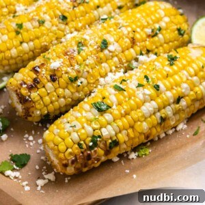 Cilantro Lime Butter Corn on the Cob (Air Fryer Recipe) 7 Cilantro lime air fryer corn on the cob sitting on brown parchment.