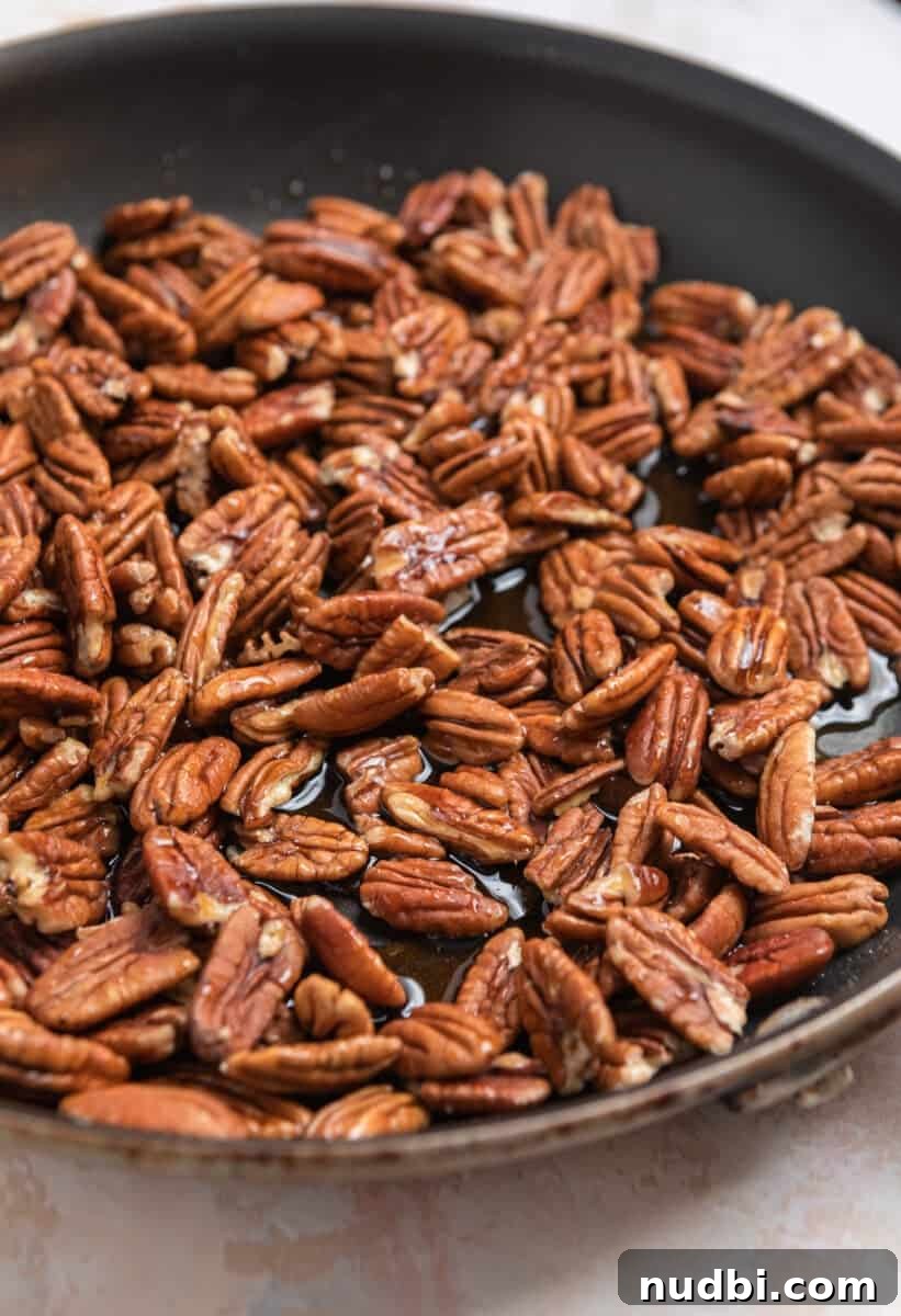 Maple-Glazed Candied Pecans Recipe for Holiday Snacking 4 Pecans in skillet with maple syrup.