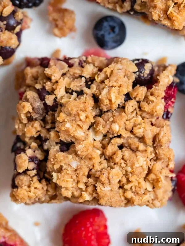 Strawberry and Peach Shortcake Recipe | Summer Dessert Guide 16 Mixed berry bar with oat crumble topping on parchment.
