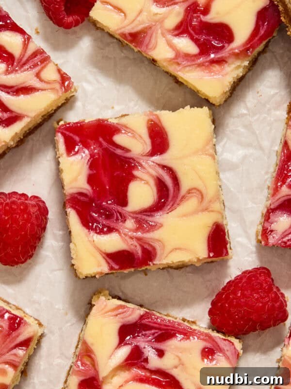 Strawberry and Peach Shortcake Recipe | Summer Dessert Guide 18 Raspberry swirl white chocolate cheesecake bars arranged on surface with fresh raspberries.