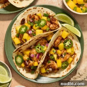 Mango Salsa Shrimp Tacos with Lime Crema 10 Three shrimp tacos on green plate topped with a salsa made of diced mango, onion and jalapeños.