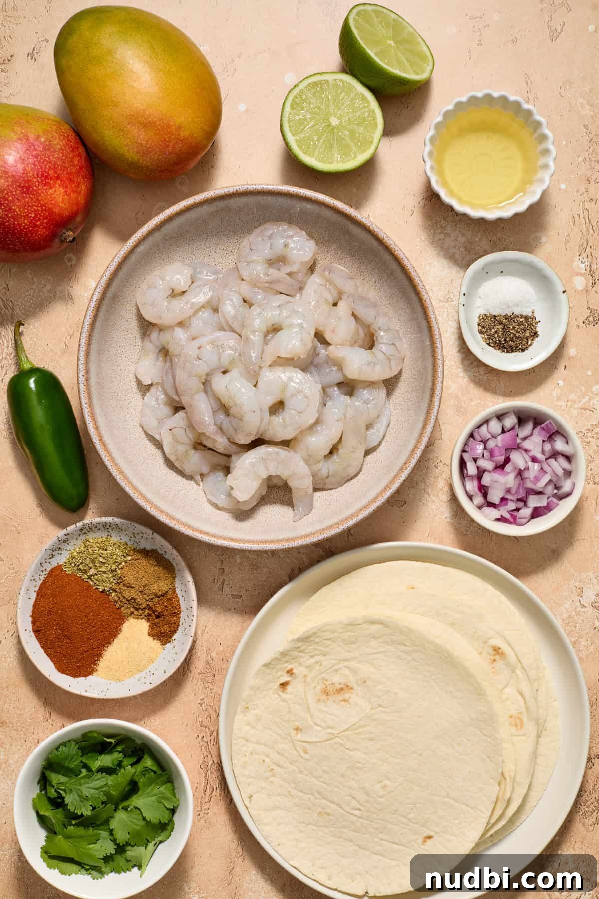 Mango Salsa Shrimp Tacos with Lime Crema 4 Raw shrimp, mango, spices, tortillas, limes and other ingredients arranged on surface.