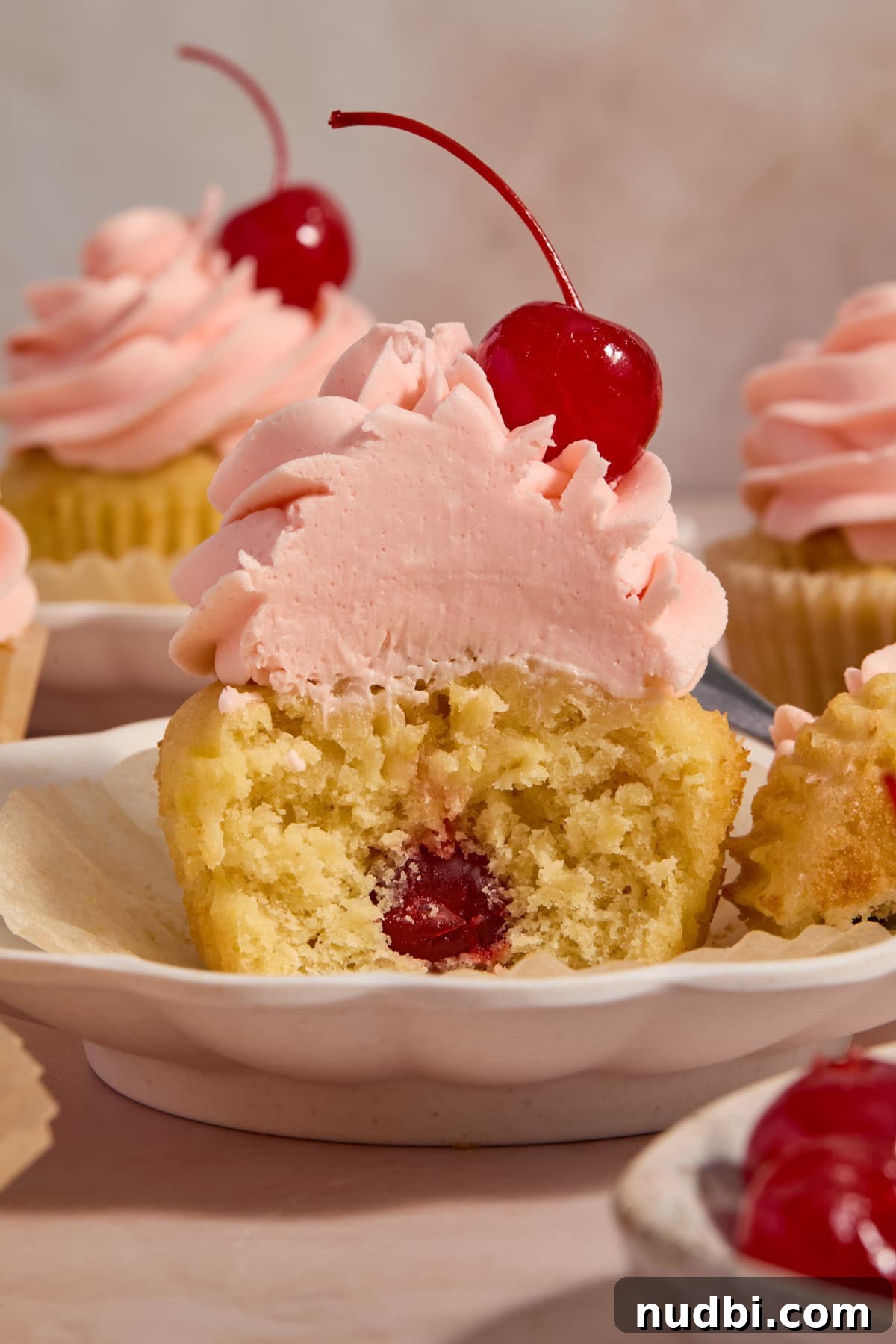 Pineapple Cupcakes with Cherry Buttercream Frosting 7 Pineapple cupcake with cherry inside topped with cherry frosting on plate.