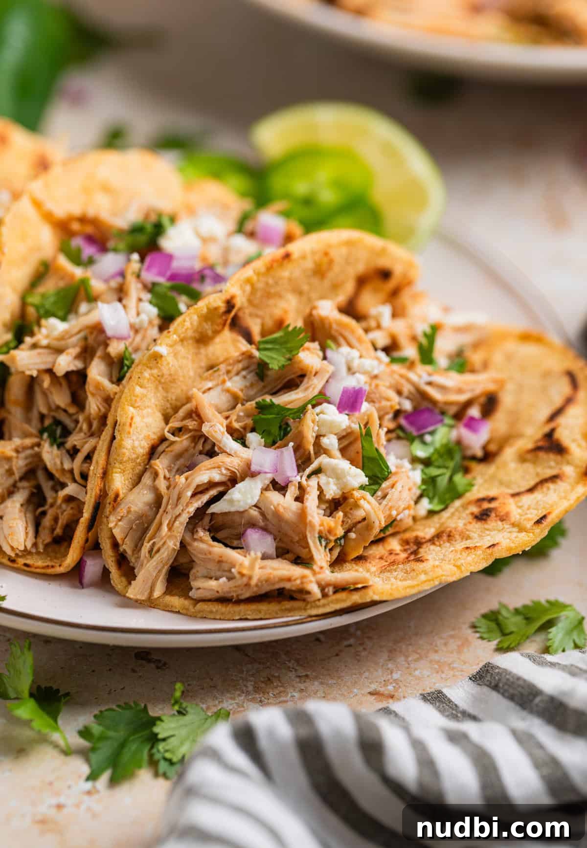 Instant Pot Shredded Chicken Tacos Recipe (30-Minute) 2 Instant pot shredded chicken tacos in charred corn tortillas topped with onion, cheese and cilantro.