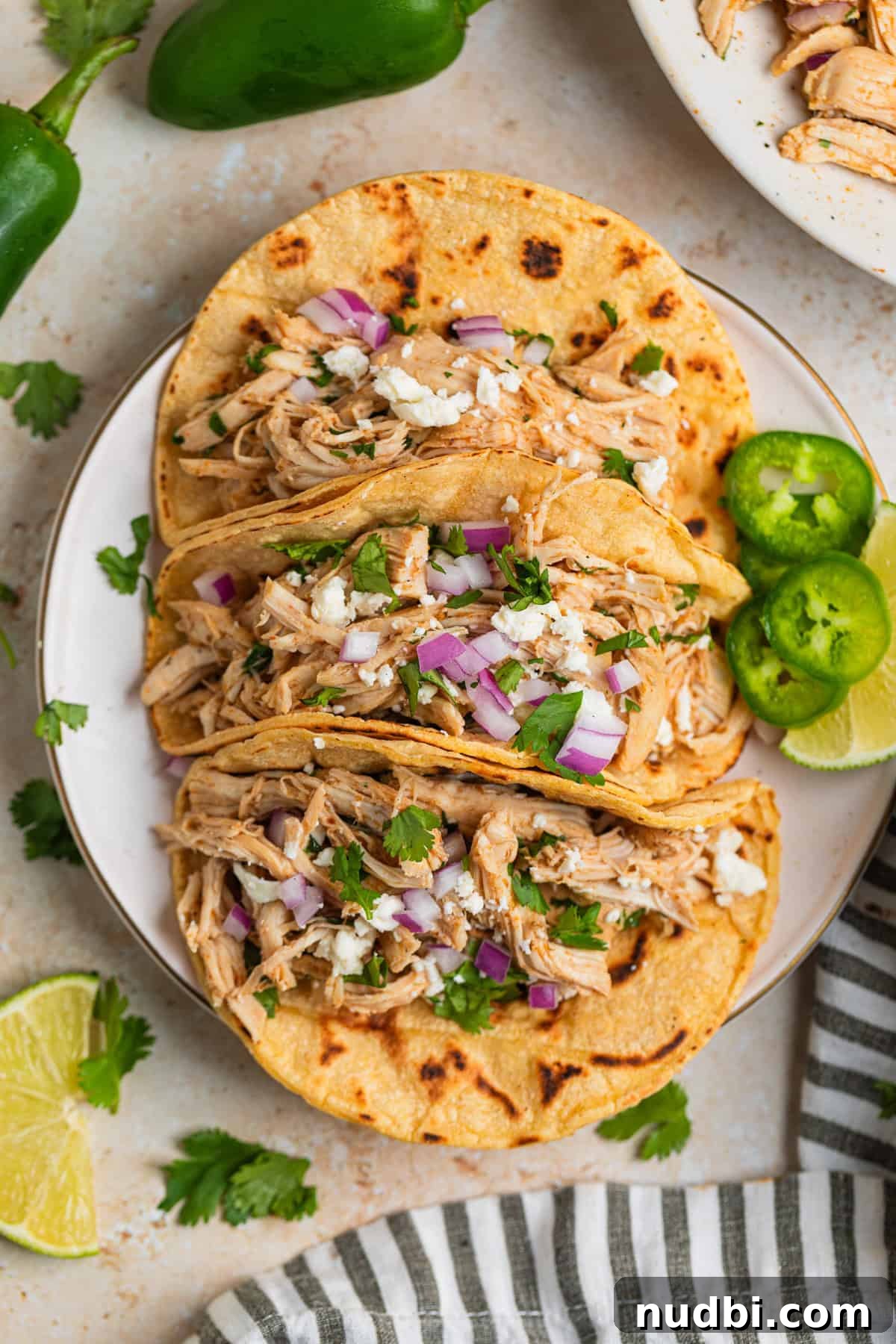 Instant Pot Shredded Chicken Tacos Recipe (30-Minute) 5 Overhead view of chicken tacos on plate with lime wedge and jalapeño slices.