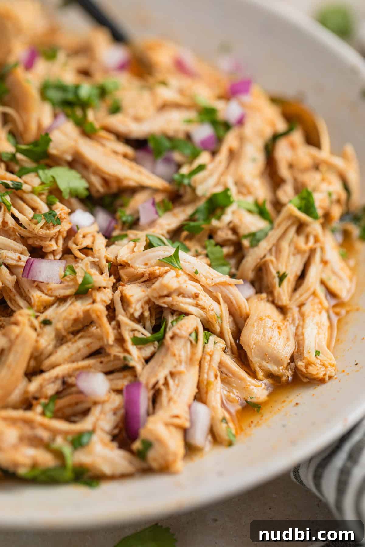 Instant Pot Shredded Chicken Tacos Recipe (30-Minute) 6 Shredded instant pot chicken in bowl with cilantro and red onion on top.