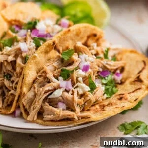 Instant Pot Shredded Chicken Tacos Recipe (30-Minute) 7 Instant Pot shredded chicken tacos on plate with queso fresco, red onion and cilantro on top.