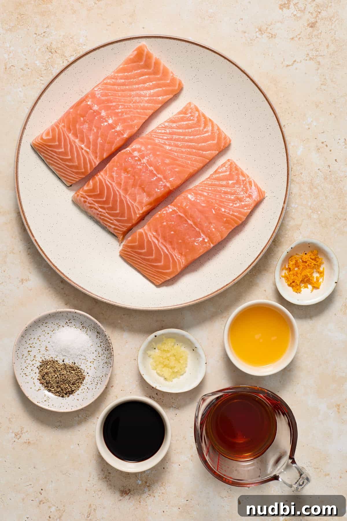Maple Citrus Glazed Salmon with Tangy Orange Lemon Sauce 3 Salmon, orange zest, maple syrup and other ingredients arranged on surface to make glazed salmon.