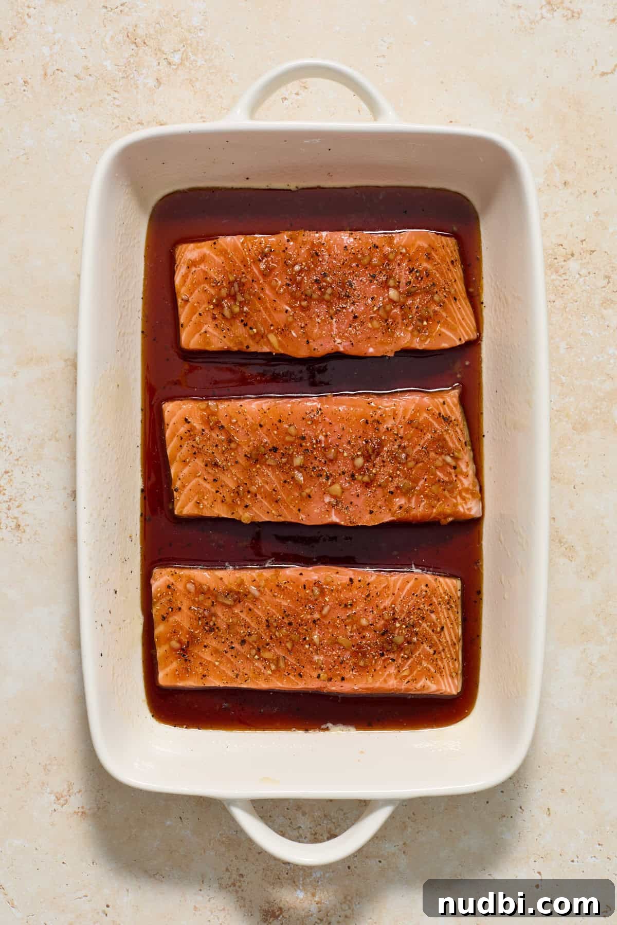 Maple Citrus Glazed Salmon with Tangy Orange Lemon Sauce 6 Salmon topped with maple glaze in baking pan.