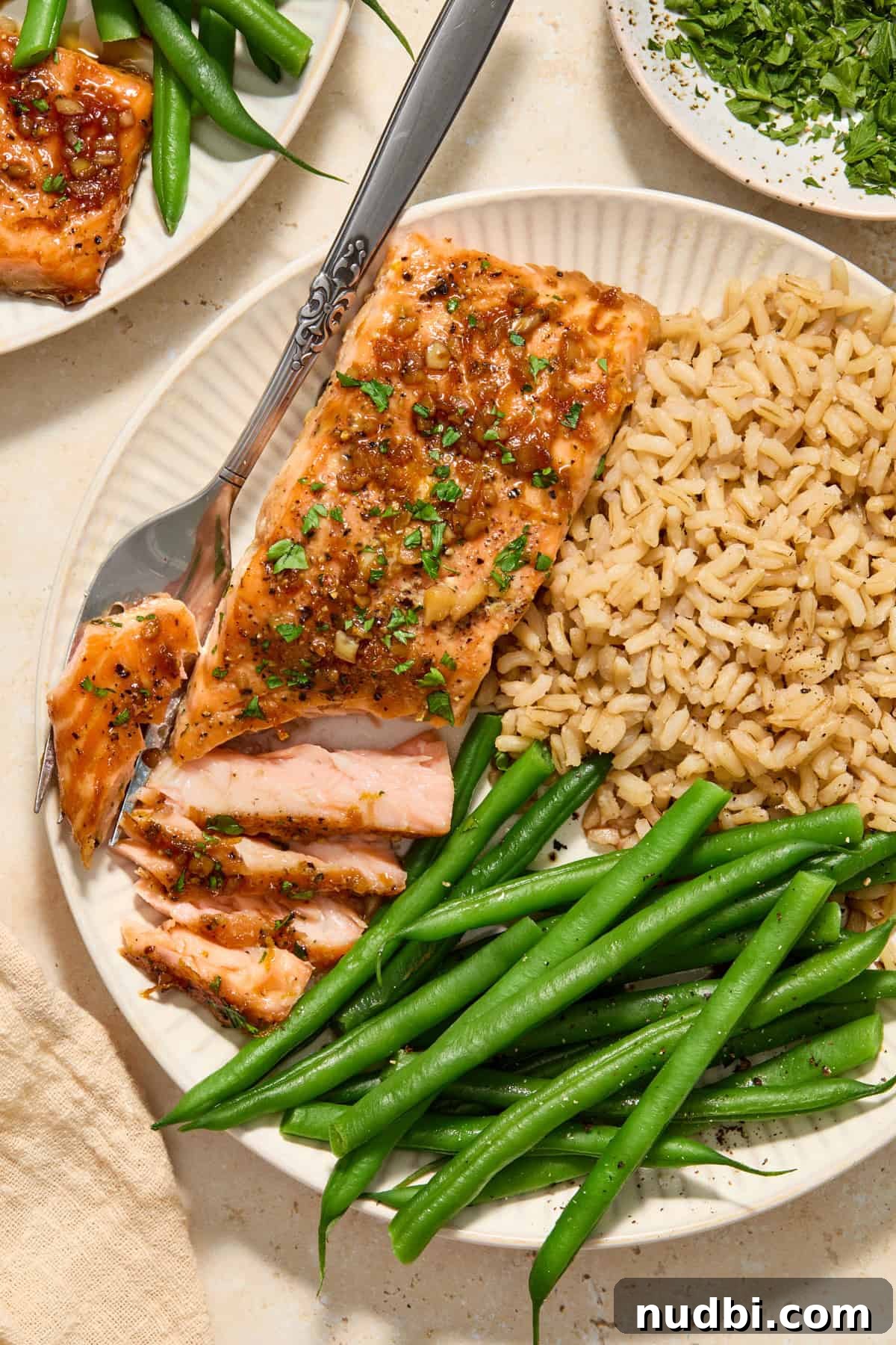 Maple Citrus Glazed Salmon with Tangy Orange Lemon Sauce 8 Overhead view of plate with salmon flaked with fork and green beans and rice on plate along with it.