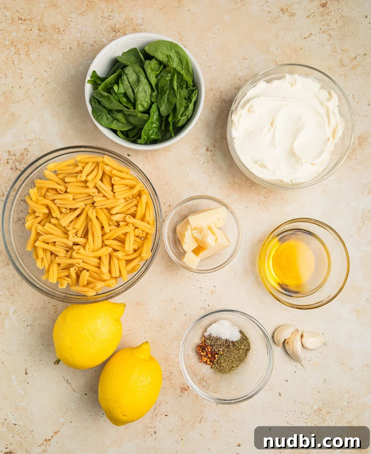 20-Minute Lemon Ricotta Pasta Recipe for Creamy Weeknight Meals 4 Pasta, lemons, spinach, olive oil and other ingredients on surface.
