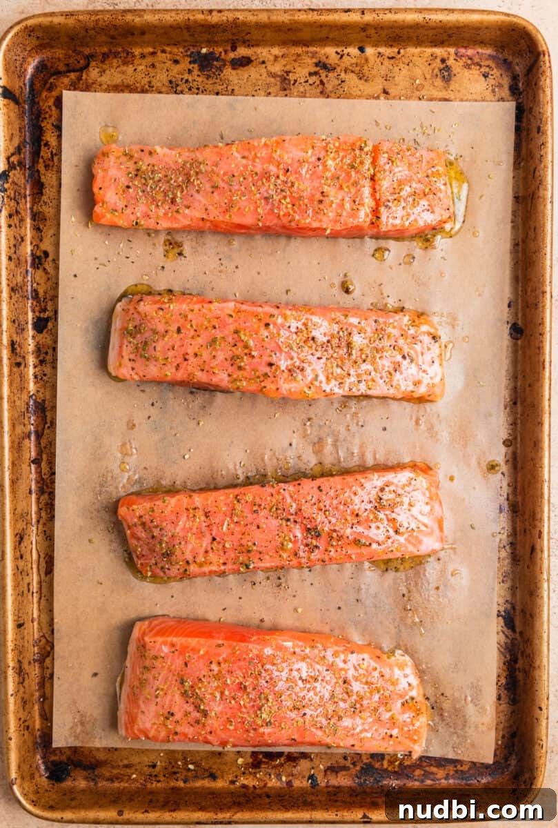Greek Salmon Rice Bowls with Tzatziki and Lemon Dill 4 Salmon filets on parchment lined baking pan topped with olive oil and seasoning before baking.