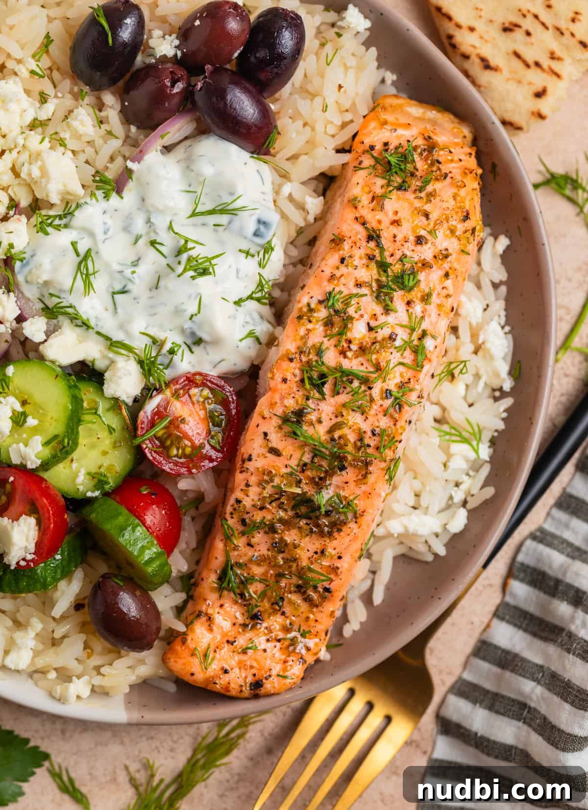 Greek Salmon Rice Bowls with Tzatziki and Lemon Dill 8 Overhead view of Greek salmon rice bowls with feta, kalamata olives, tomatoes, cucumbers and more.