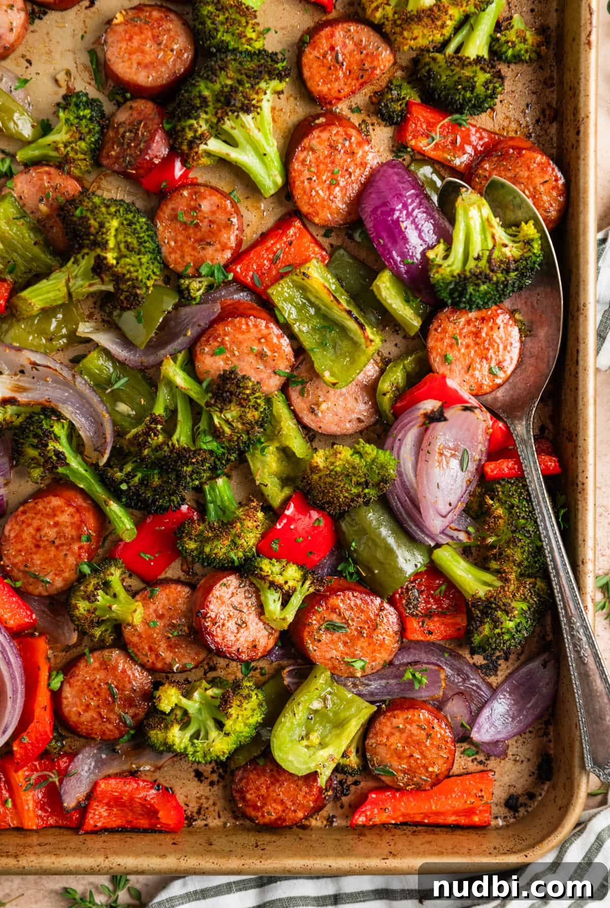 One-Pan Sausage and Veggie Sheet Pan Dinner 2 Sausage sheet pan dinner with serving spoon scooping into the food.
