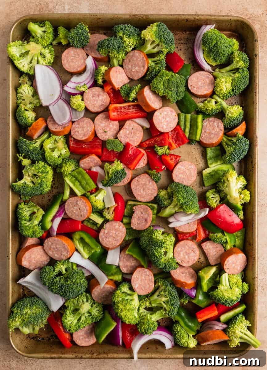 One-Pan Sausage and Veggie Sheet Pan Dinner 4 Kielbasa sausage sliced, chopped peppers and broccoli and onions on sheet pan.